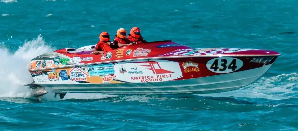 Race boat #434 in red, white and blue sponsor livery running fast across turquoise water