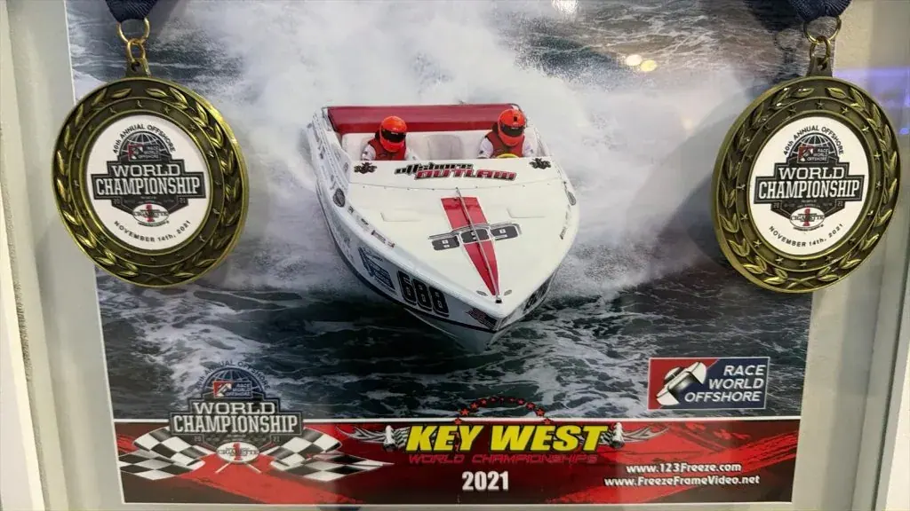Two Race World Offshore Key West World Championship 2021 medals beside a race-boat photo