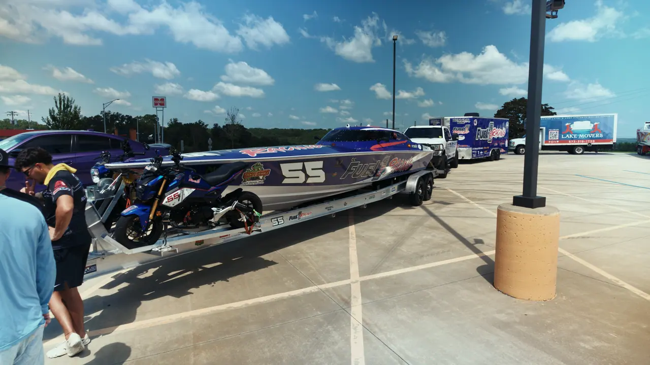 The #55 Phantom on its trailer behind a navy pickup in the race pits, crew walking past