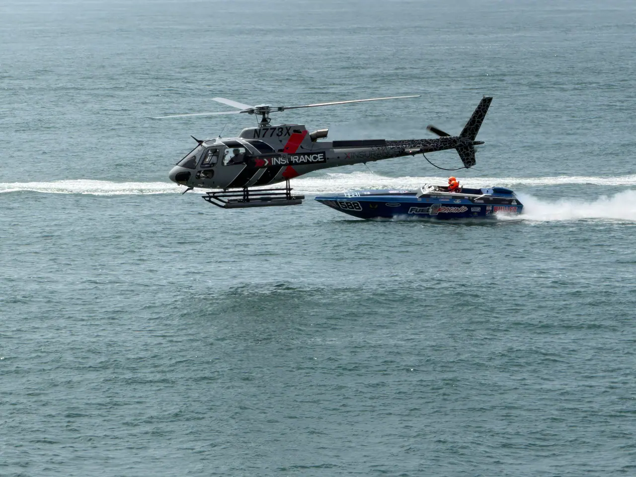 Two Fuel 1 drivers in blue and white race suits giving a thumbs up on a wet dock beside the #55 boat